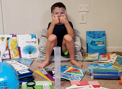 A curious boy exploring his world through books and supplies on the floor.