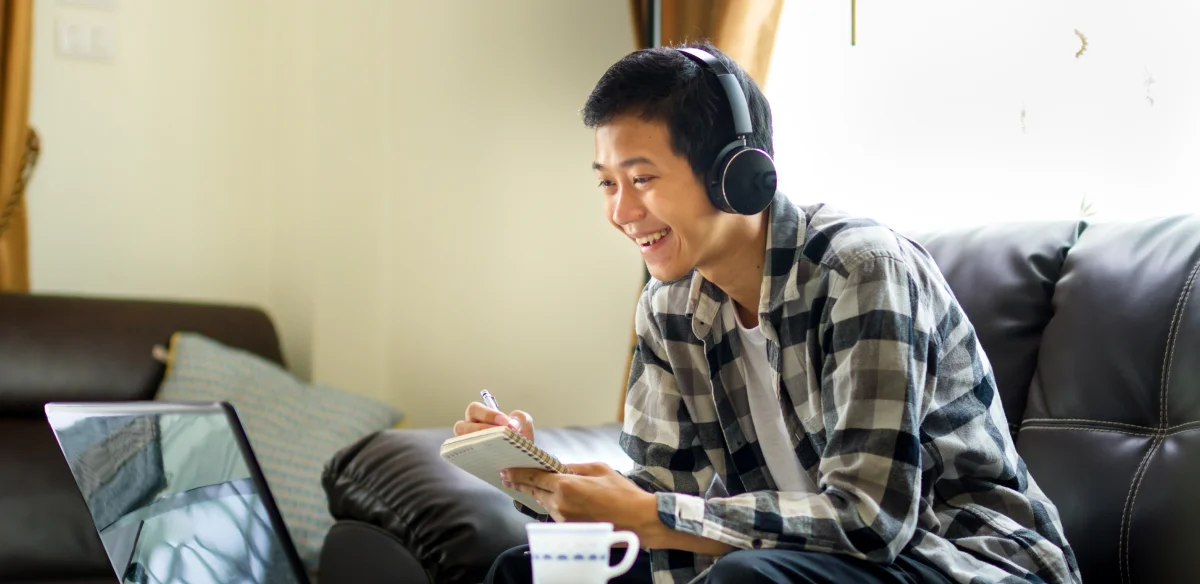 Student taking notes and using a headset